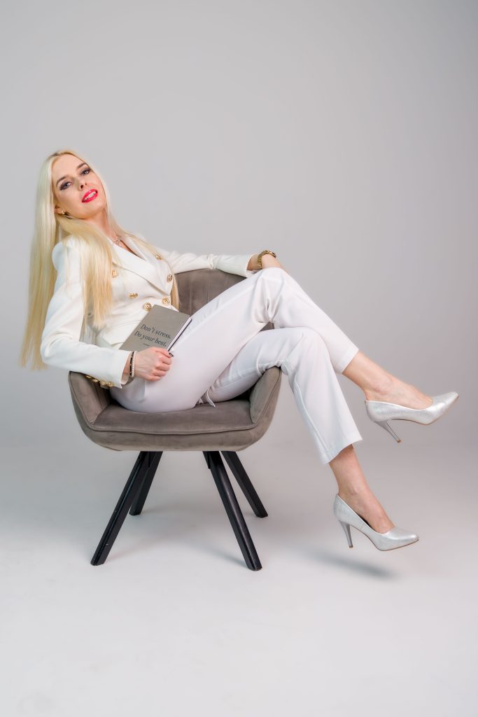 Sesja biznesowa studyjna Poznań z modelką z długimi blond włosami siedzącą na fotelu